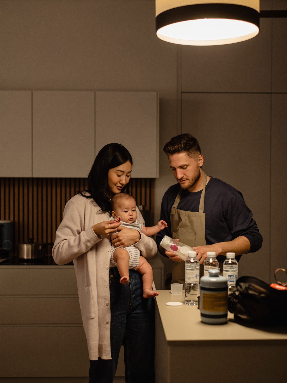 A young couple calmly preparing a baby bottle by lantern light during a power outage